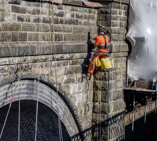 The old viaduct bridge at Millers Dale, Derbyshire in the Peak District being repaired with mortar by building engineers.
